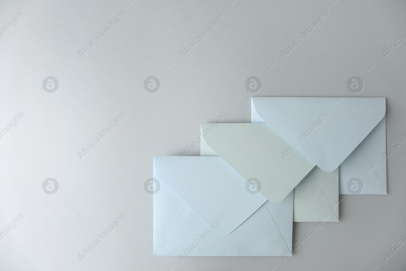Photo of White paper envelopes on light grey background, top view. Space for text