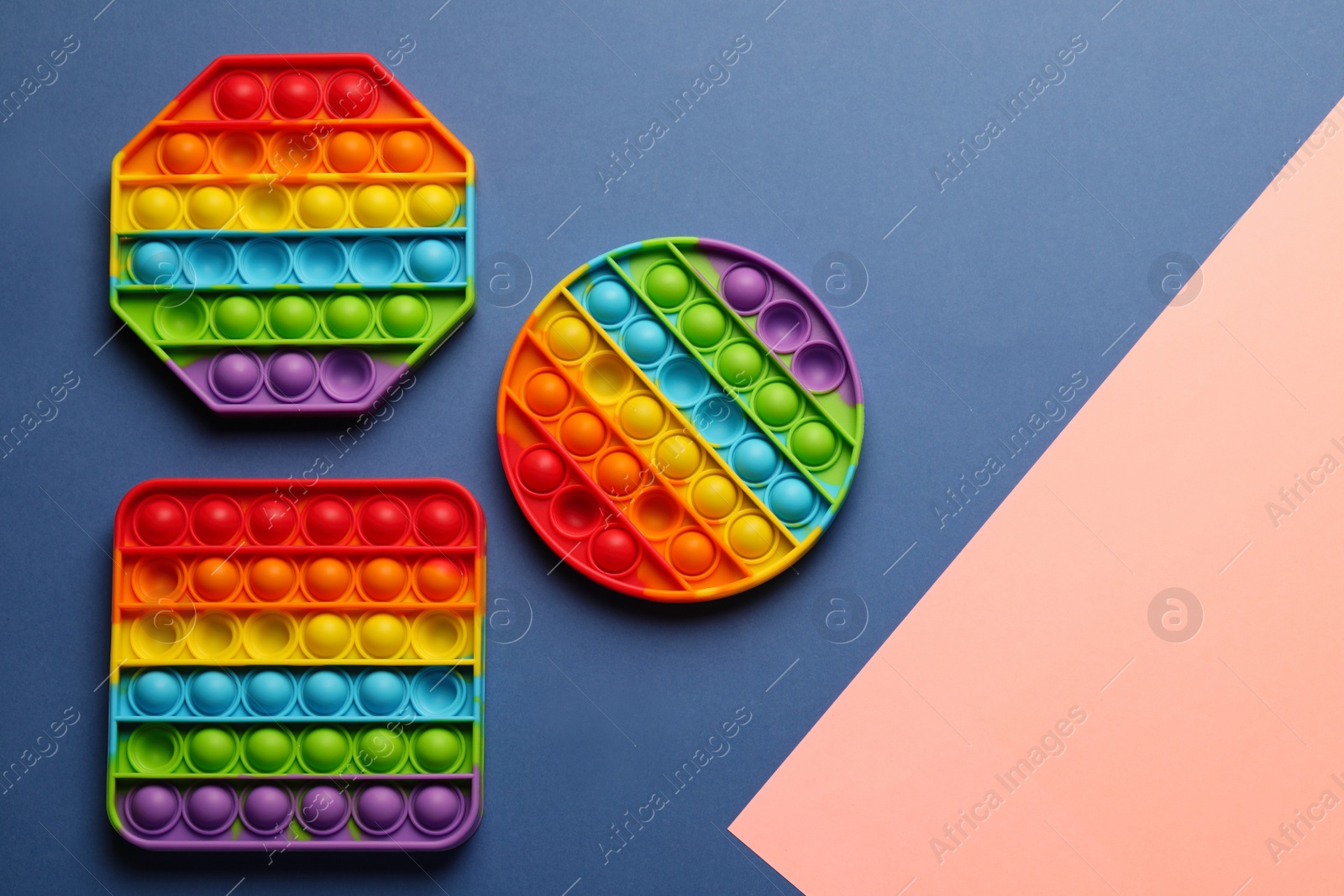 Photo of Rainbow pop it fidget toys on color background, flat lay. Space for text