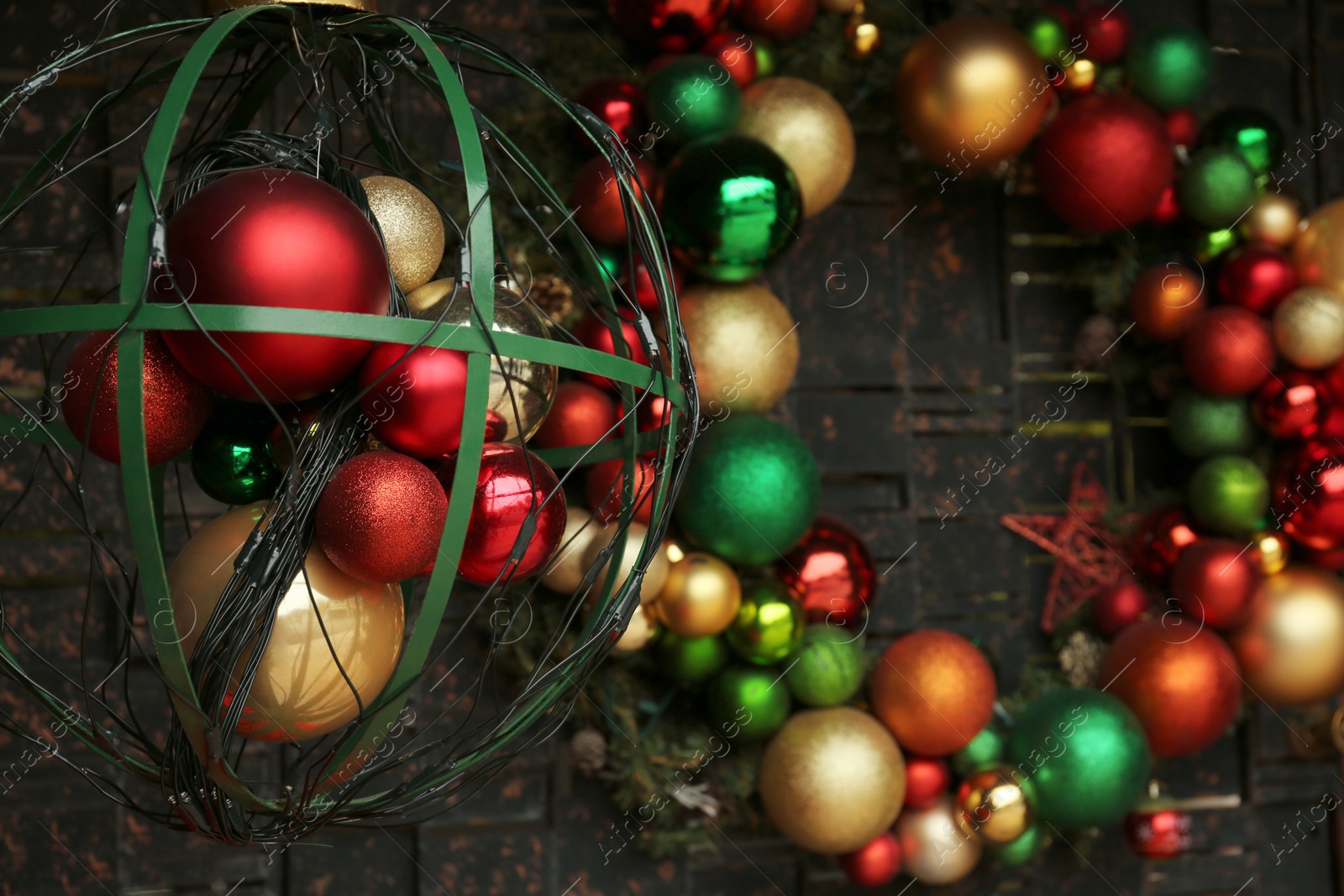 Photo of Beautiful colorful Christmas baubles near grey wall, closeup. Festive street decorations