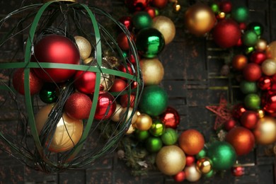 Photo of Beautiful colorful Christmas baubles near grey wall, closeup. Festive street decorations