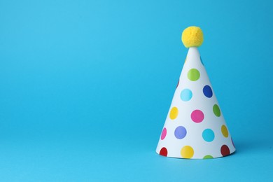 Photo of Colorful party hat on light blue background, space for text