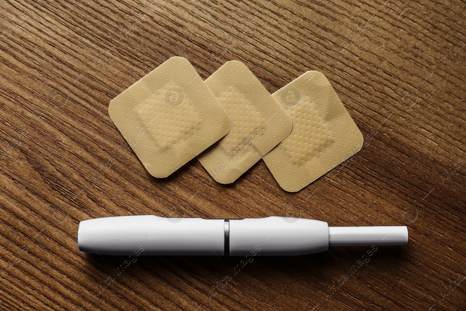 Photo of Nicotine patches and electronic cigarette on wooden table, flat lay