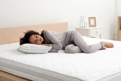 Photo of Young African American woman sleeping on bed with comfortable mattress and pillow at home