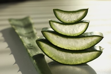 Photo of Fresh aloe vera slices on white table, closeup. Space for text