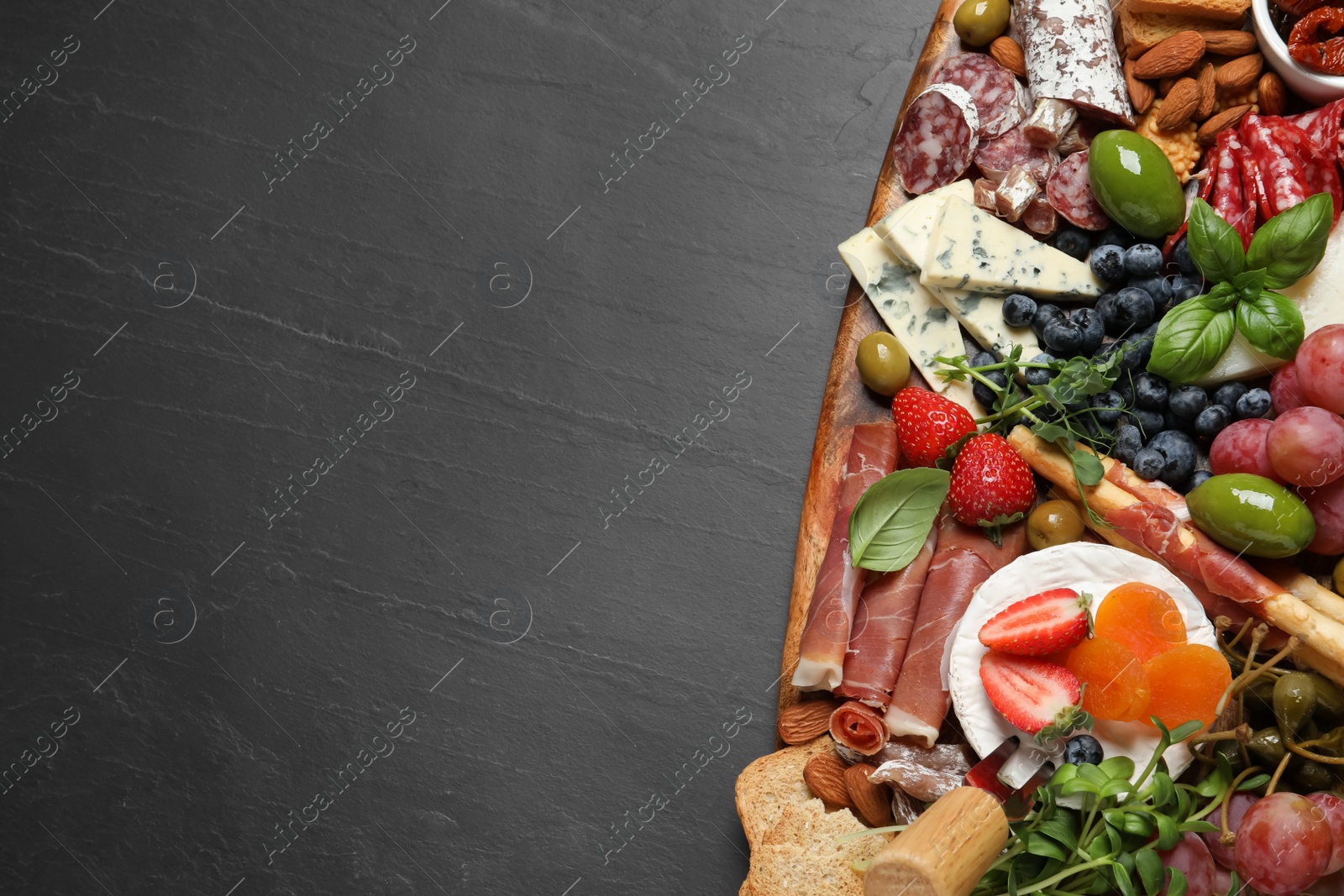 Photo of Set of different delicious appetizers served on black table, top view. Space for text