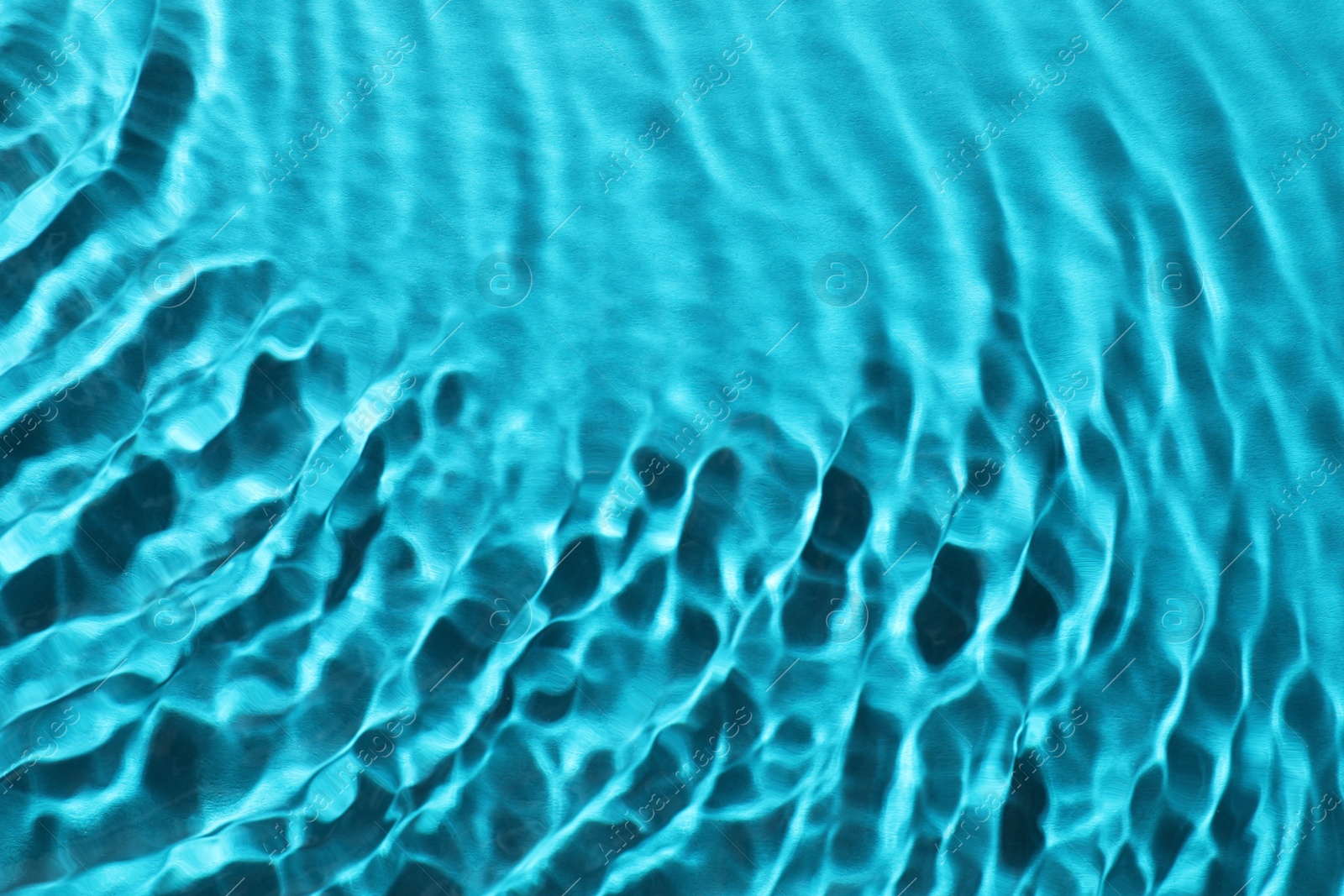 Image of Rippled surface of clear water on light blue background, closeup