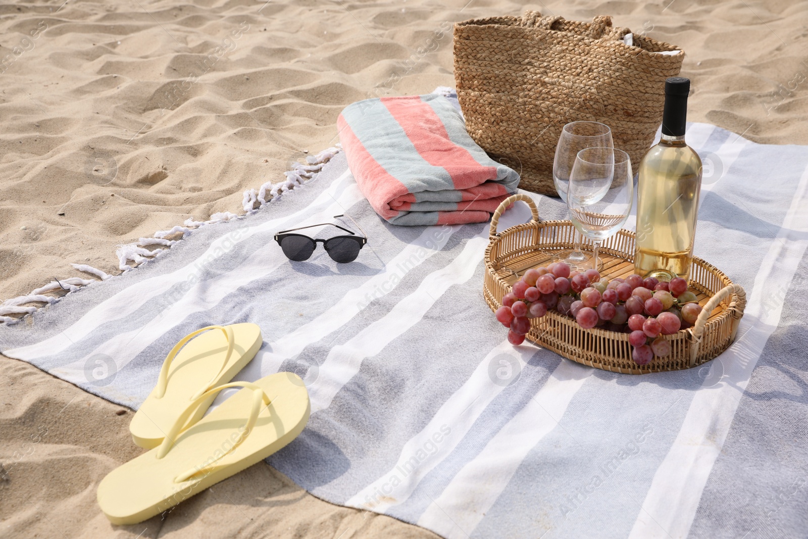 Photo of Bag, blanket, wine and other stuff for beach picnic on sand