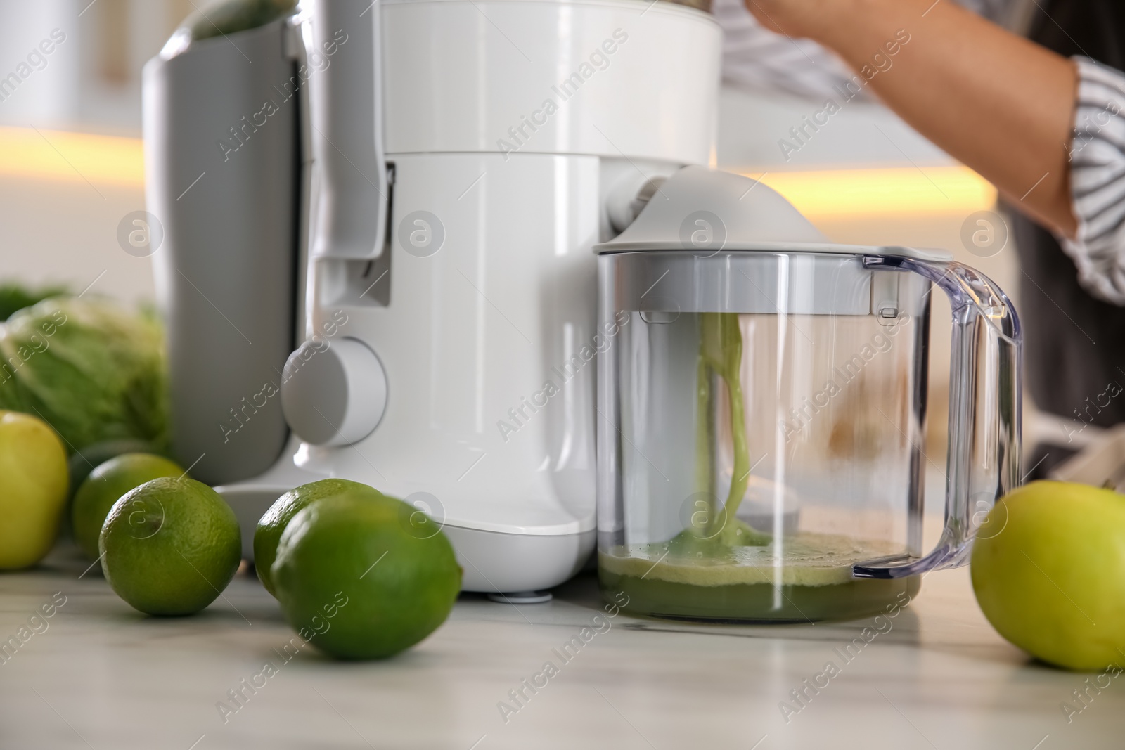 Photo of Young woman making tasty fresh juice at table in kitchen, closeup