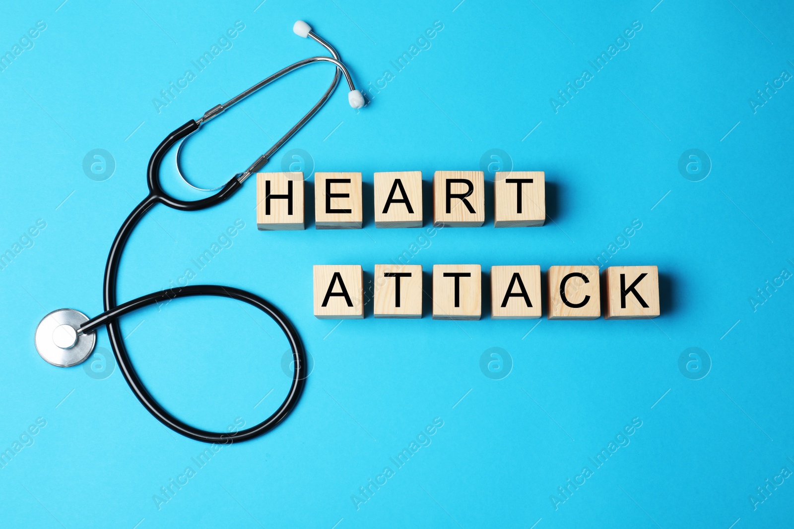 Photo of Wooden cubes with words HEART ATTACK and stethoscope on color background, top view