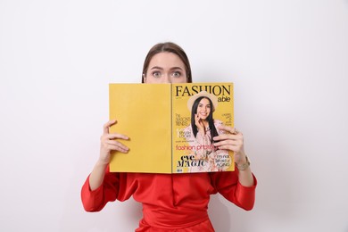 Photo of Young woman with fashion magazine near white wall