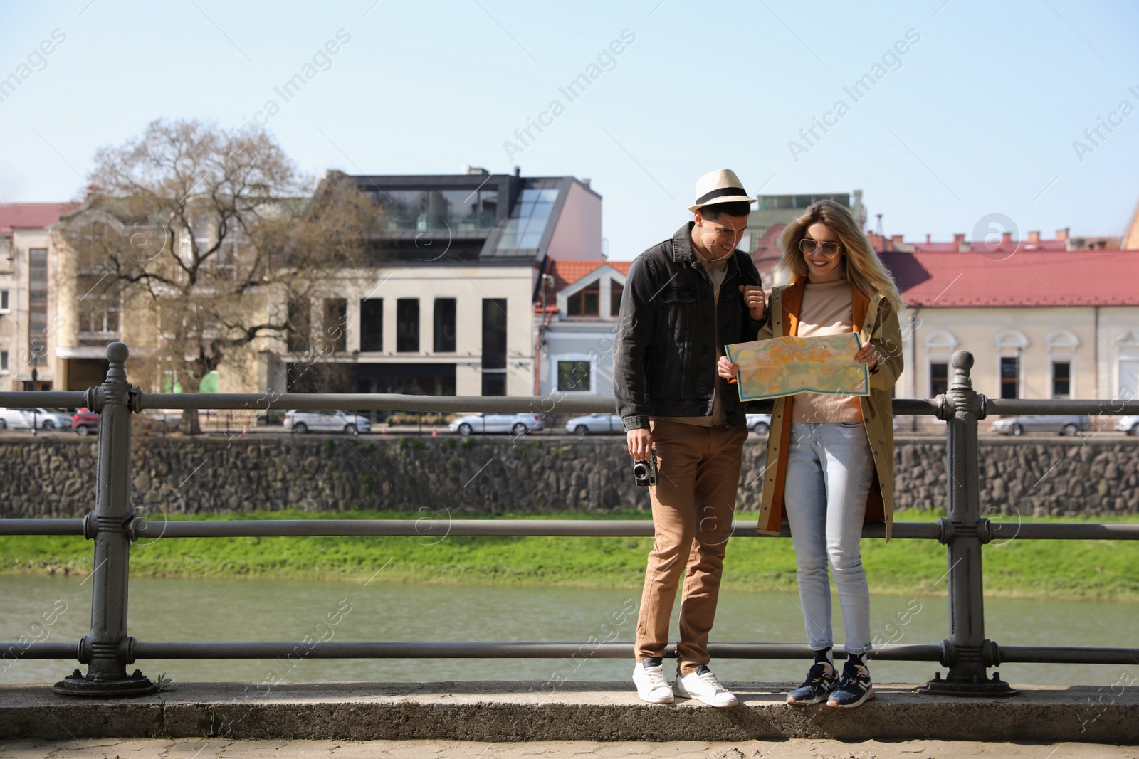 Photo of Couple of tourists with map on city street near beautiful river