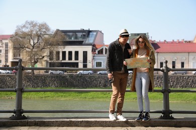 Photo of Couple of tourists with map on city street near beautiful river