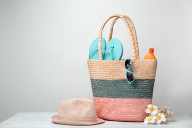 Bag with beach objects on table against light background