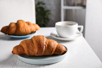 Photo of Tasty fresh croissants and coffee on white wooden table