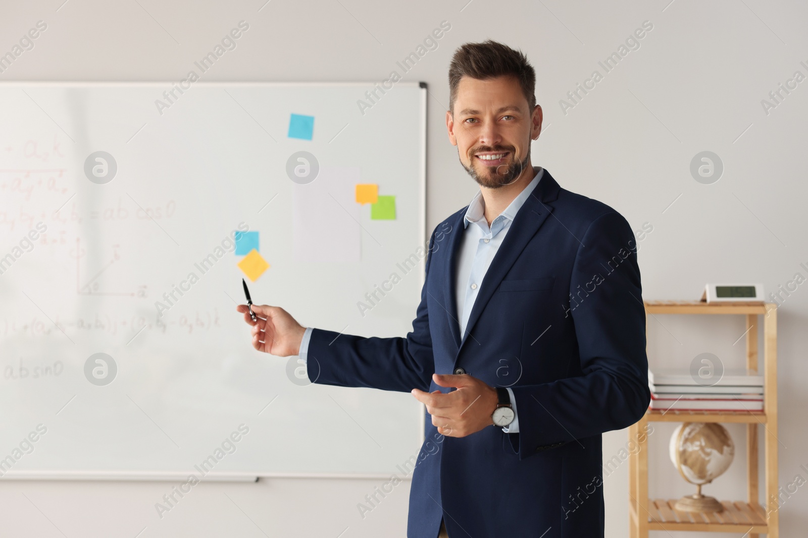 Photo of Happy teacher explaining mathematics at whiteboard in classroom