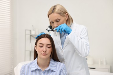 Trichologist with dermatoscope examining patient`s hair in clinic