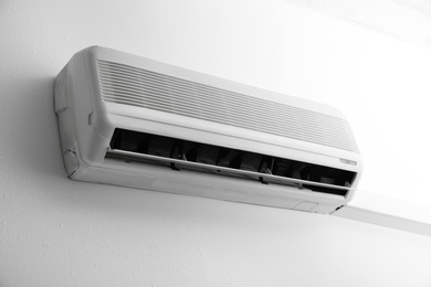 Photo of Modern air conditioner on white wall indoors