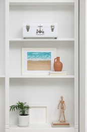 Photo of Shelving unit with different decor elements in room. Interior design