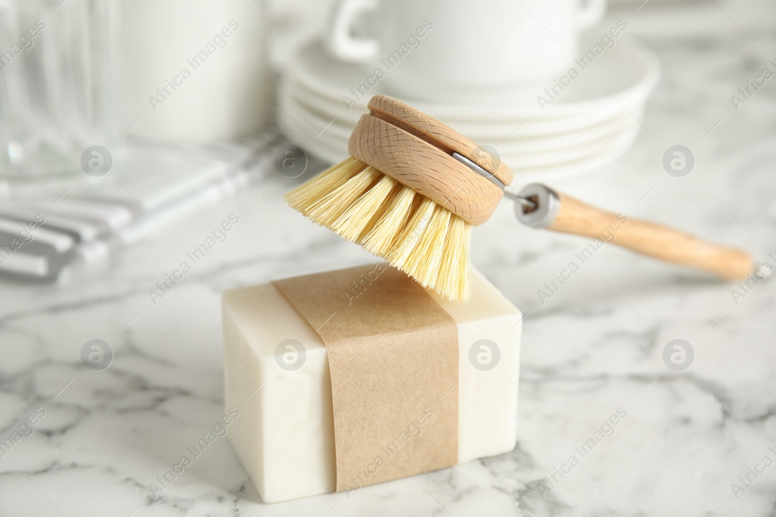 Photo of Cleaning brush and soap bar for dish washing on white marble table indoors, closeup