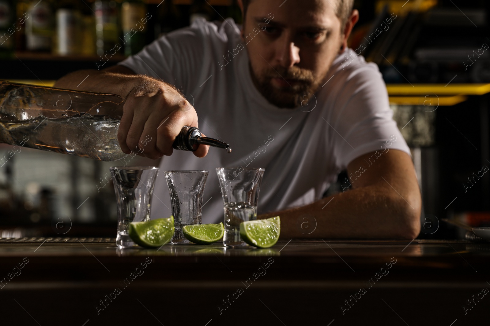 Photo of Bartender pouring Mexican Tequila into shot glass at bar counter, closeup