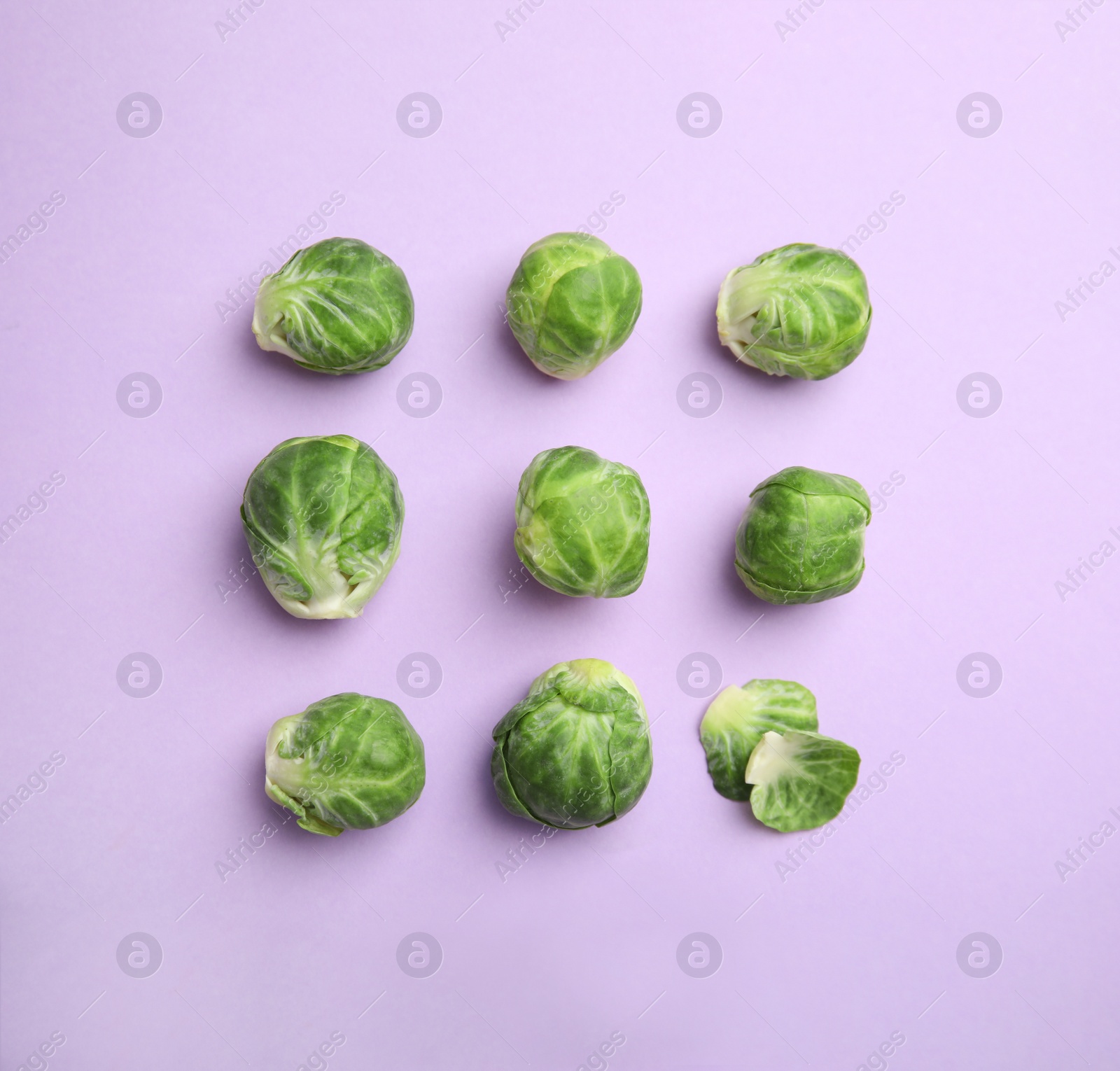 Photo of Fresh Brussels sprouts on violet background, flat lay