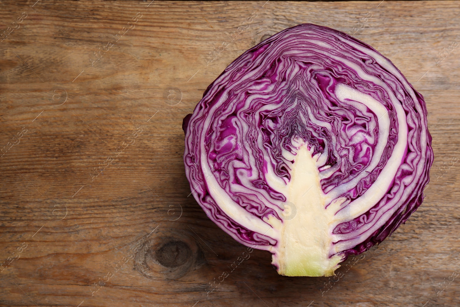 Photo of Half of ripe red cabbage on wooden table, top view. Space for text