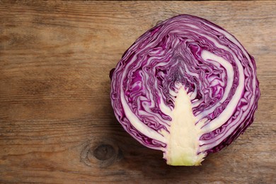 Photo of Half of ripe red cabbage on wooden table, top view. Space for text