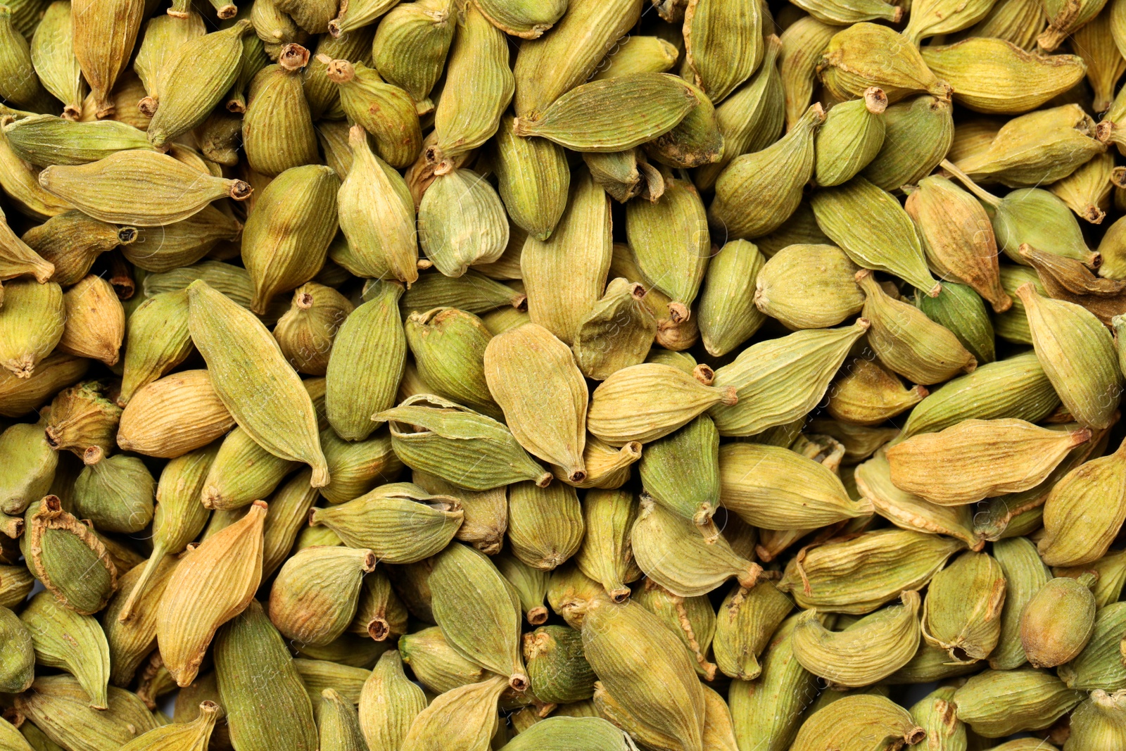 Photo of Pile of dry green cardamom pods as background, top view