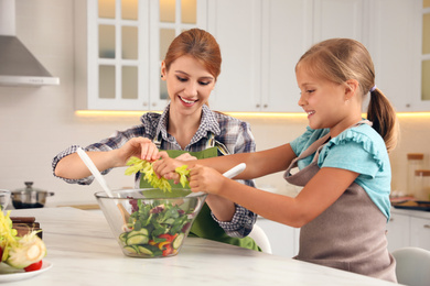 Mother and daughter cooking salad together in kitchen