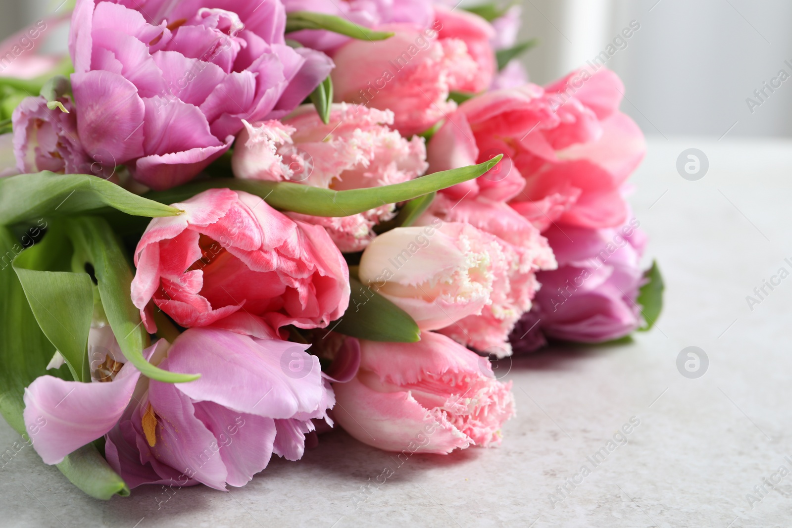 Photo of Beautiful bouquet of colorful tulip flowers on light gray table, closeup