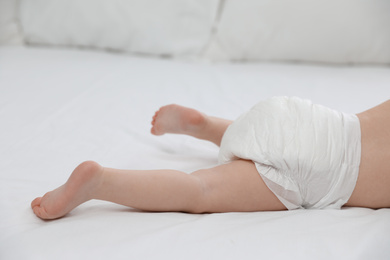 Photo of Cute little baby in diaper on bed, closeup