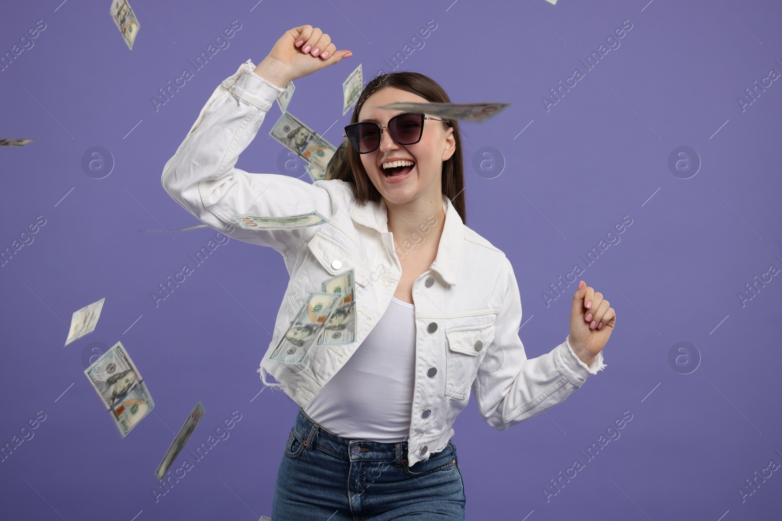 Photo of Happy woman under money shower on purple background