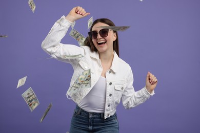 Photo of Happy woman under money shower on purple background