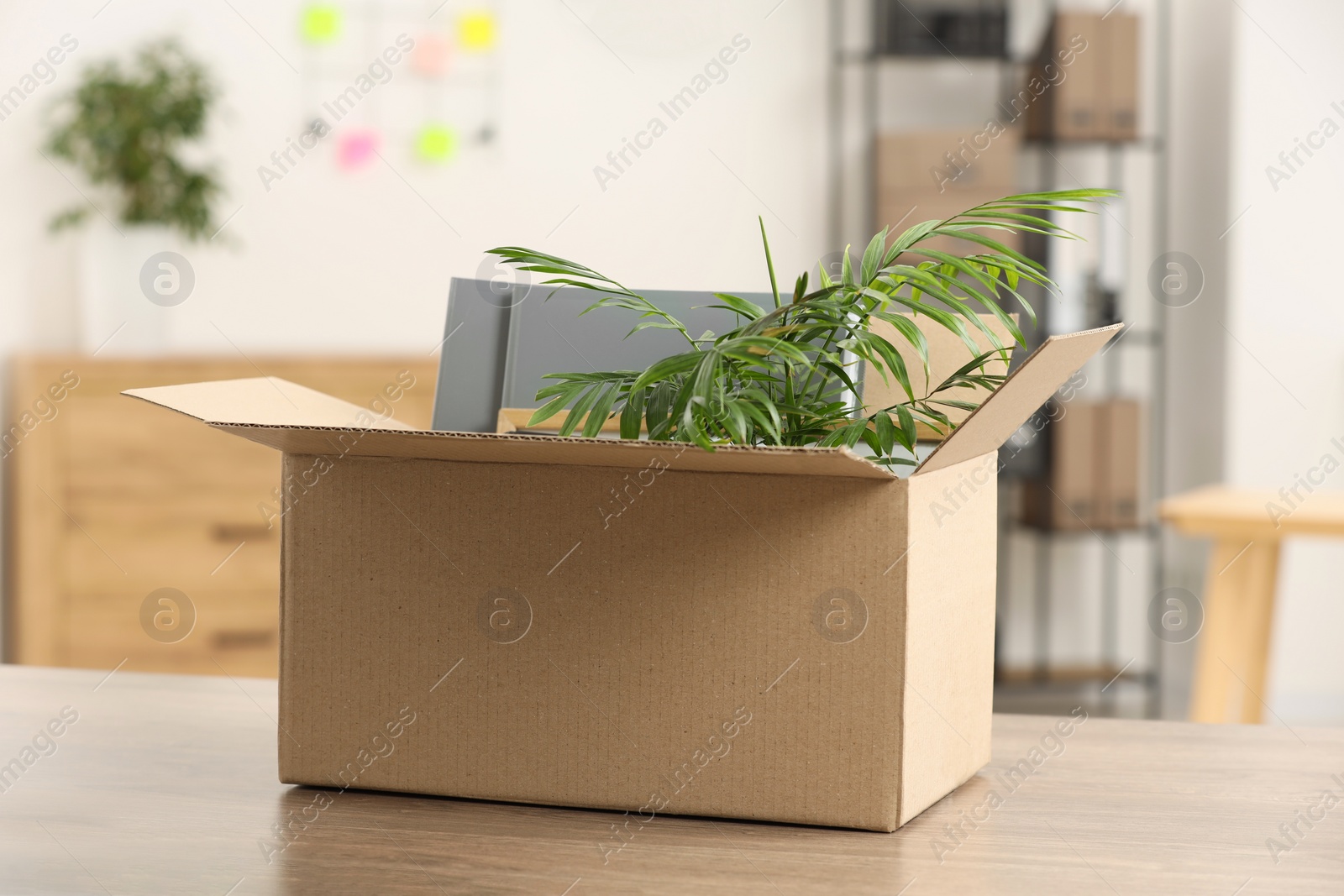 Photo of Unemployment problem. Box with worker's personal belongings on table in office