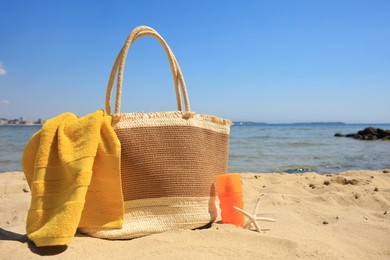 Photo of Sunscreen, starfish, bag and towel on beach, space for text. Sun protection care