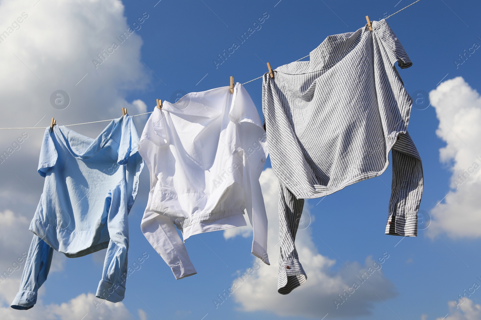 Photo of Clean clothes hanging on washing line against sky. Drying laundry