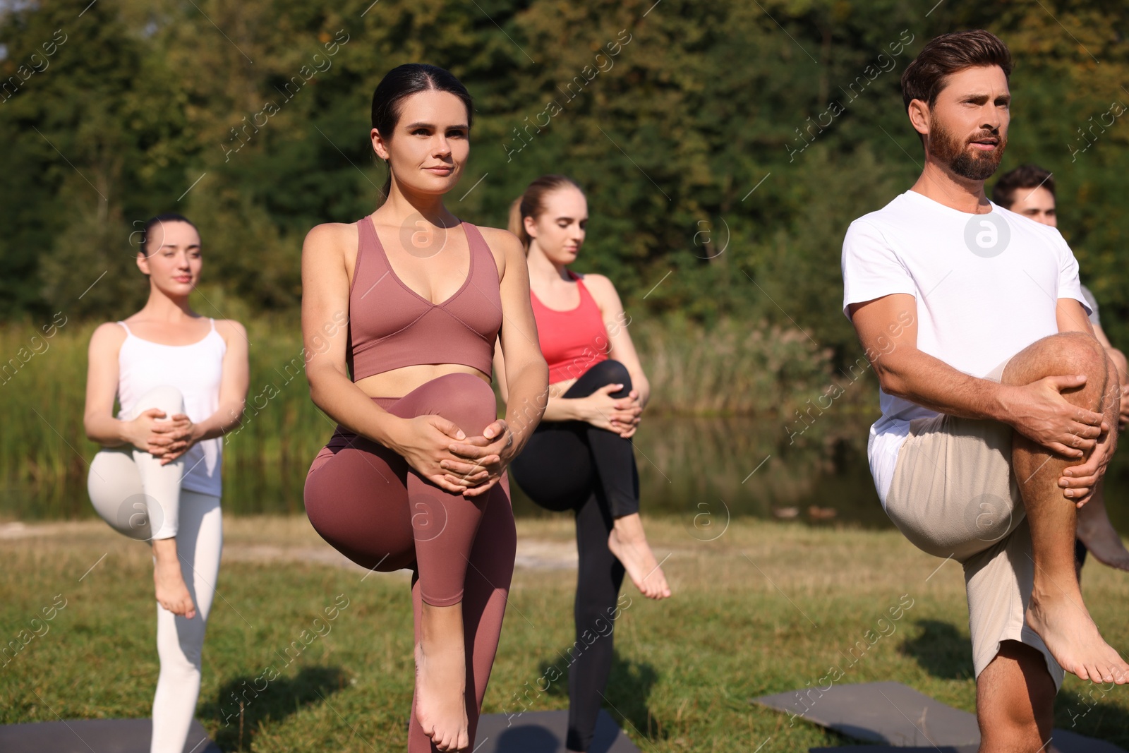 Photo of Group of people practicing yoga on mats outdoors