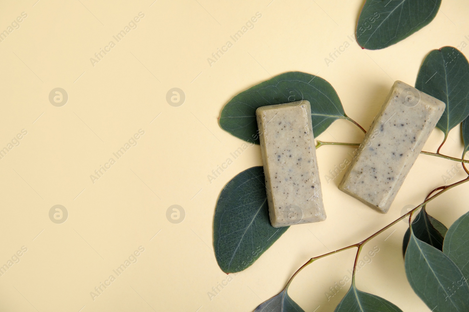 Photo of Flat lay of soap bars and green leaves on beige background, space for text. Eco friendly personal care product