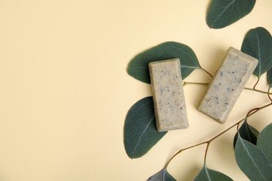 Photo of Flat lay of soap bars and green leaves on beige background, space for text. Eco friendly personal care product