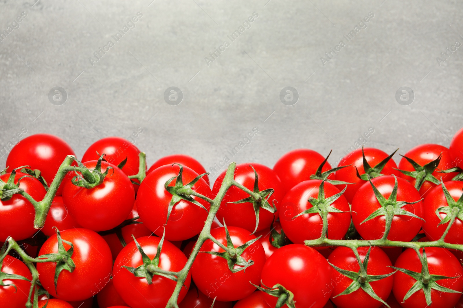 Photo of Heap of fresh cherry tomatoes on stone background, top view. Space for text