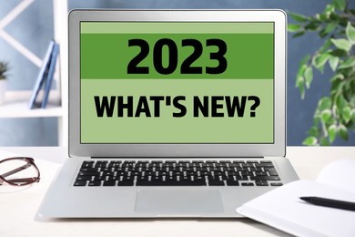 Image of Future trends. 2023 What's New? text on laptop display. Modern device on table