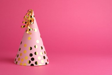 Photo of One beautiful party hat with serpentine streamers on pink background. Space for text
