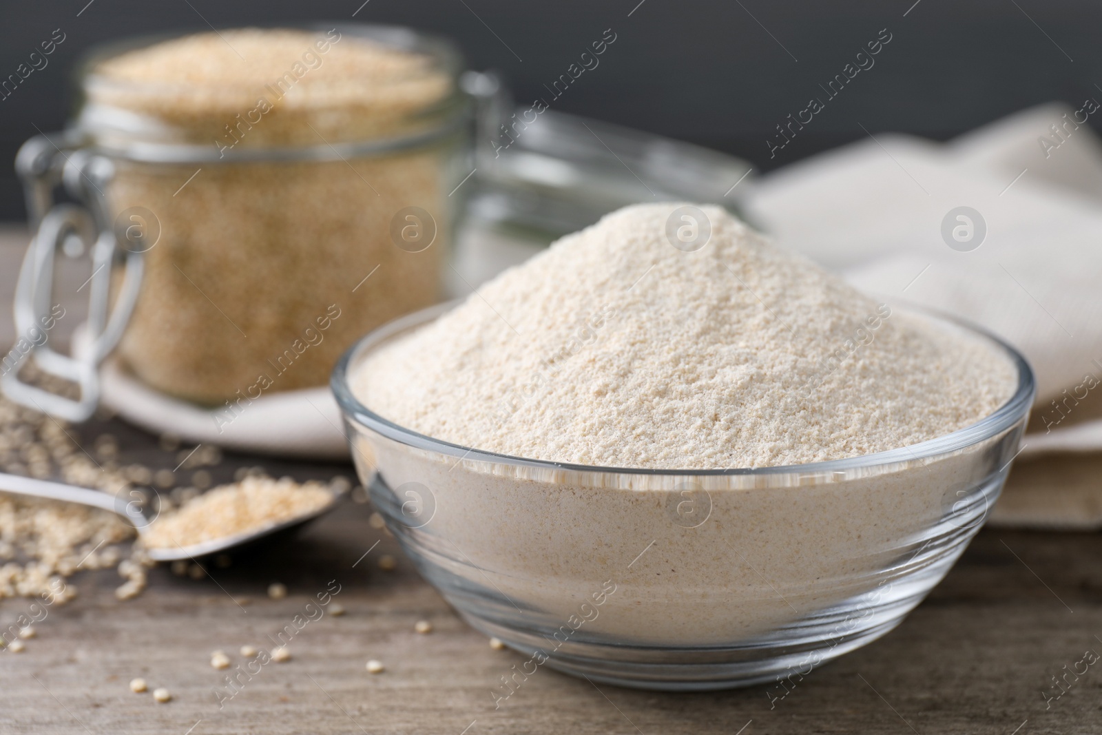 Photo of Glass bowl with quinoa flour and seeds on table, closeup