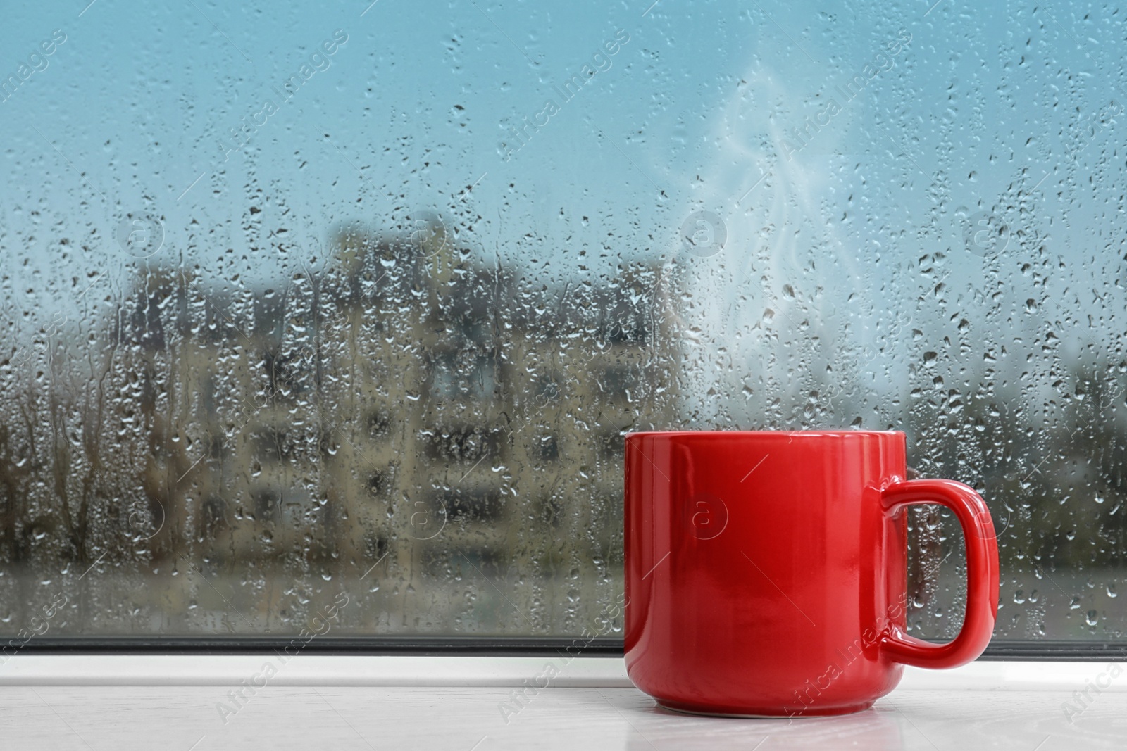 Image of Cup of hot drink near window on rainy day