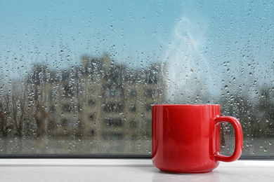 Image of Cup of hot drink near window on rainy day