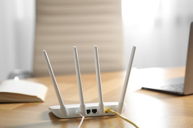 Photo of New modern Wi-Fi router on wooden table indoors