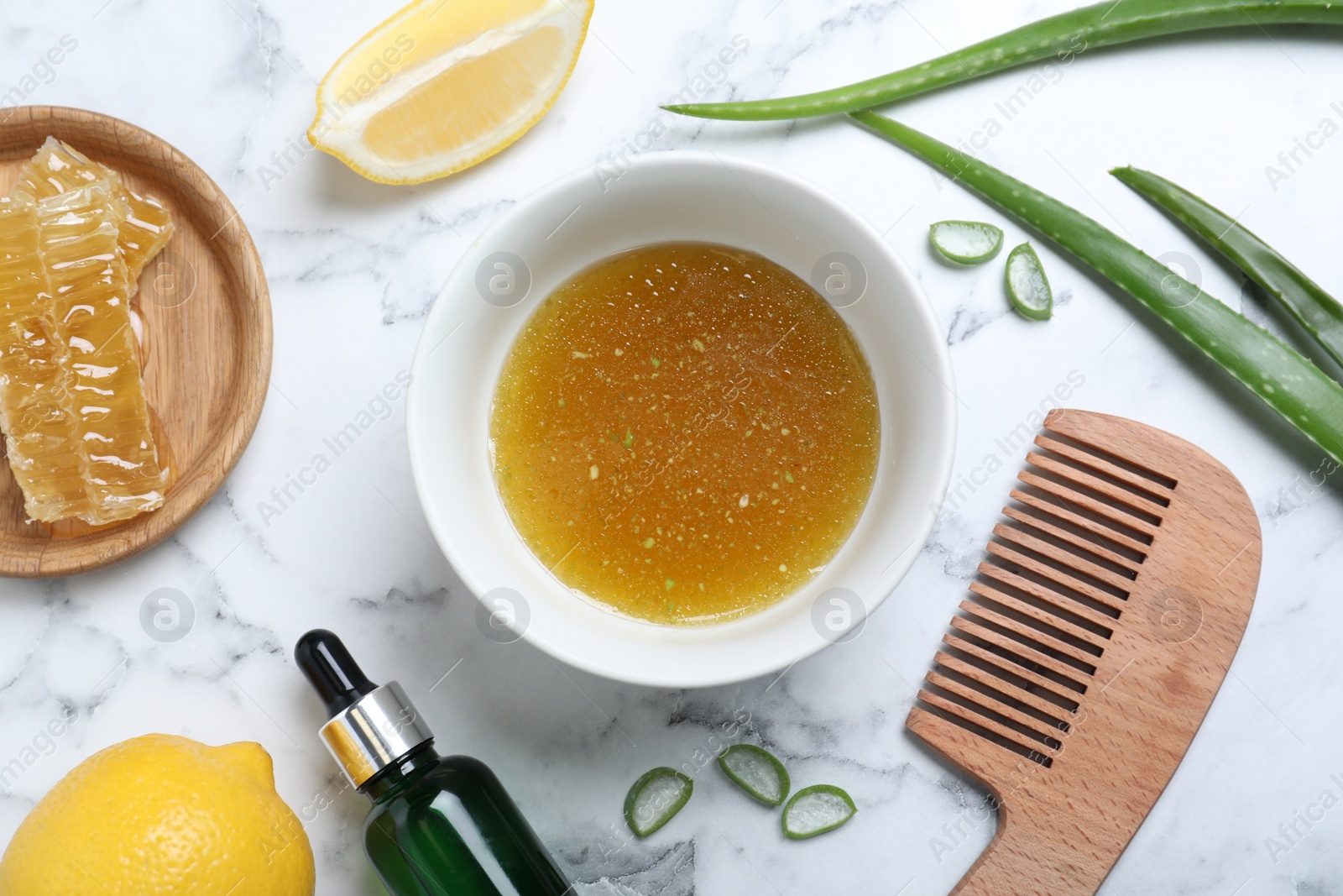 Photo of Homemade hair mask in bowl, ingredients and bamboo comb on white marble table, flat lay