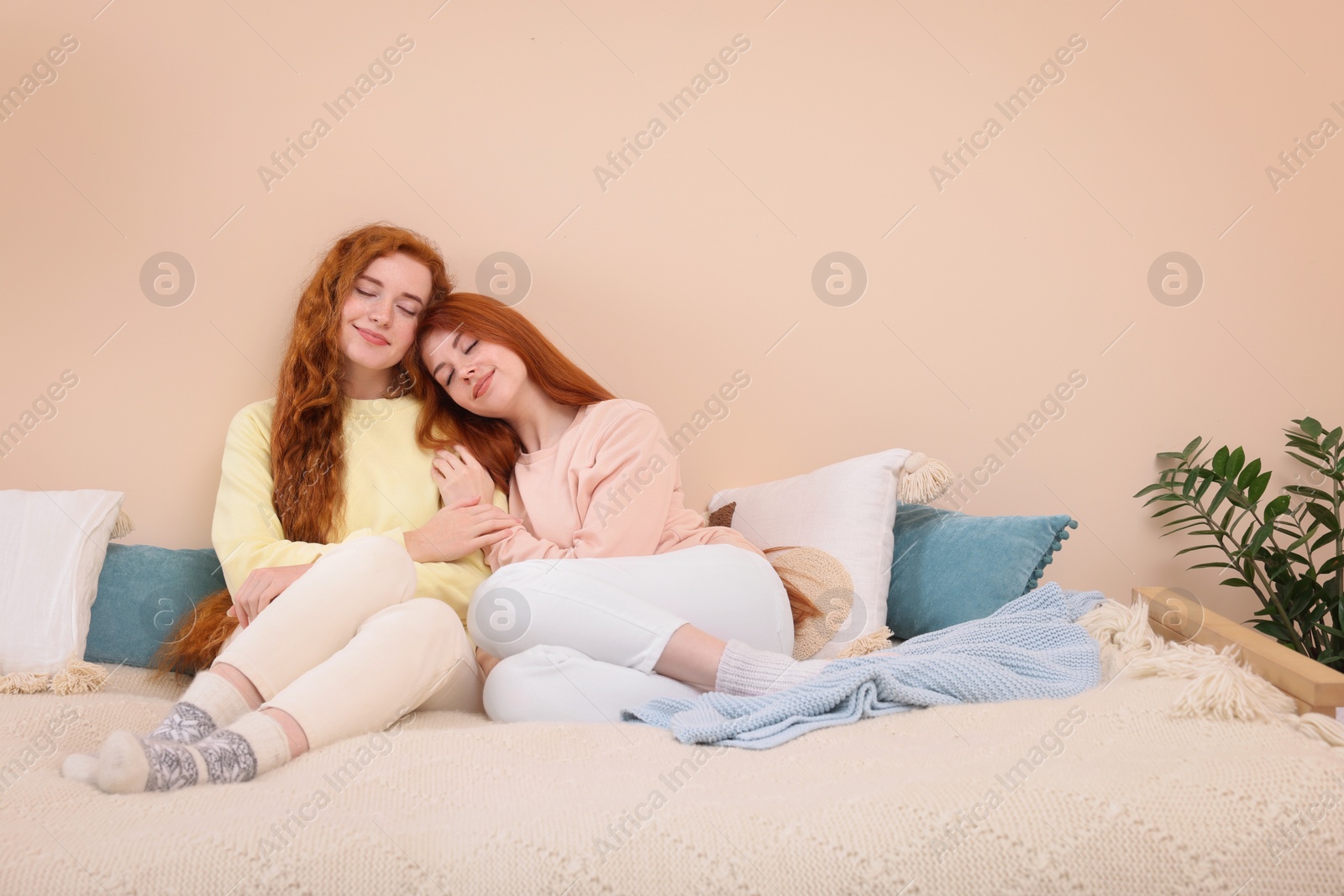 Photo of Portrait of beautiful young redhead sisters in bedroom. Space for text