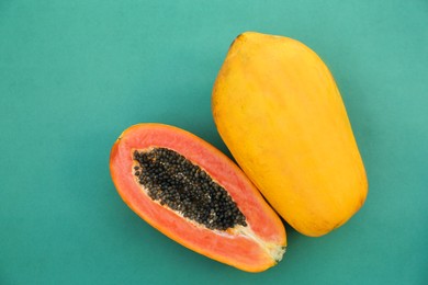 Photo of Fresh ripe cut and whole papaya fruits on light blue background, flat lay