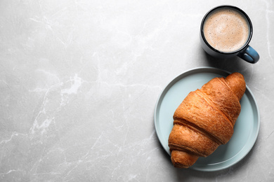 Fresh croissant and coffee on light grey marble table, flat lay. Space for text